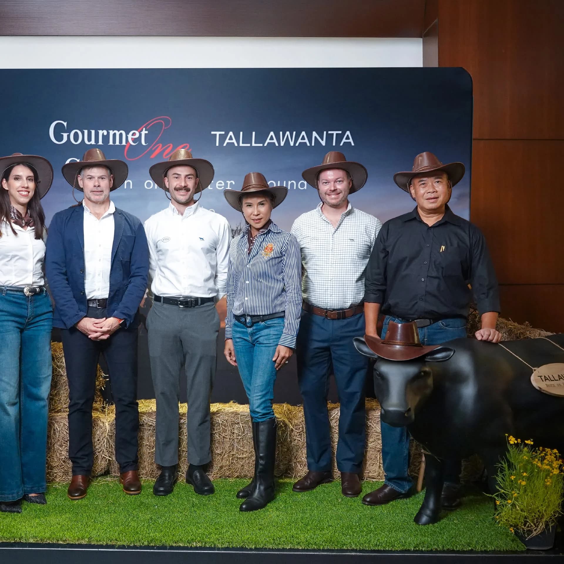 Guests posing beside a TALLAWANTA and Gourmet One backdrop at the launch dinner.